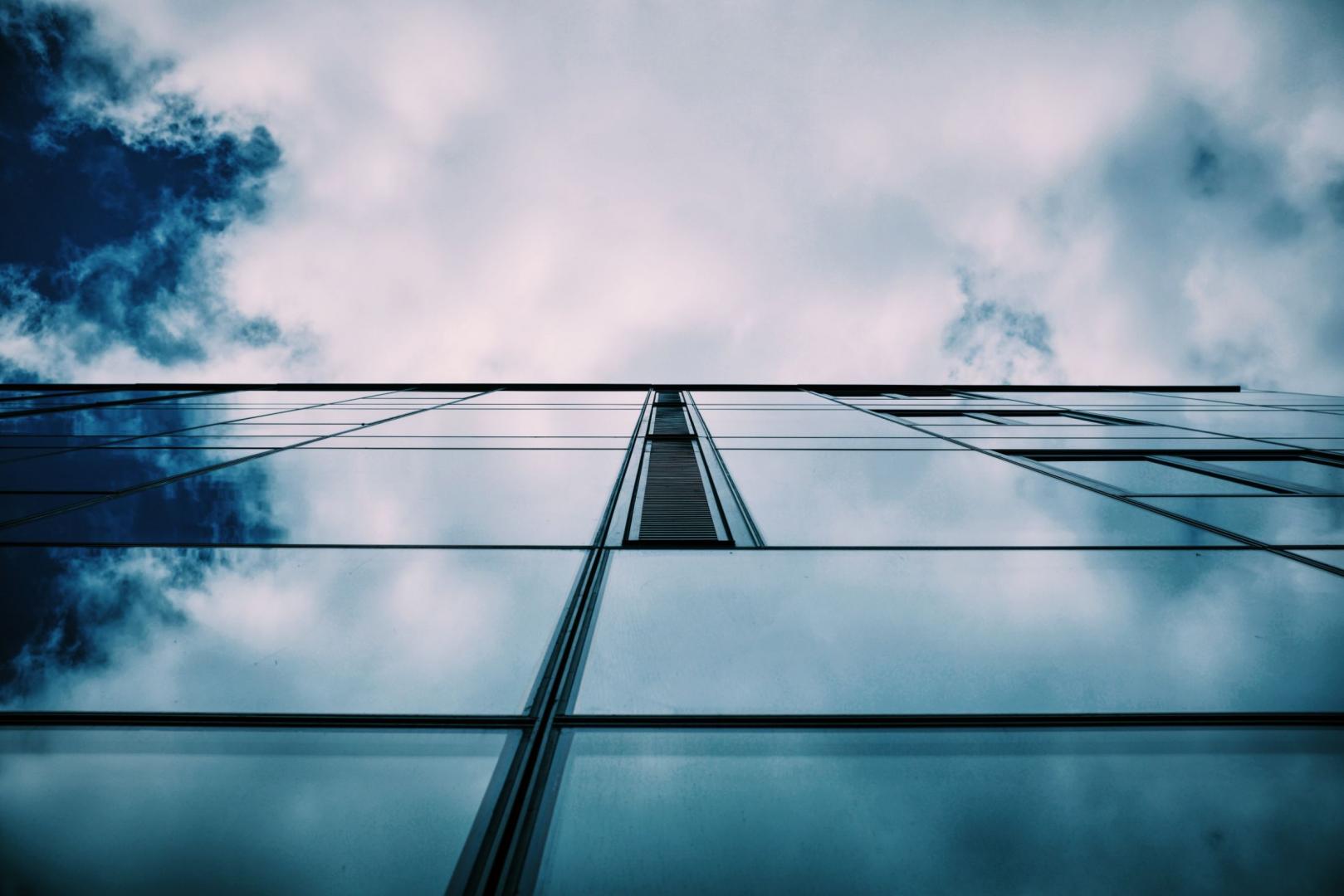Glass facade reflecting cloudy sky